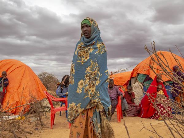 In Somalia, a teenage girl stands in the middle of a displaced peoples' camp.