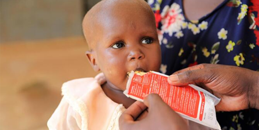 Child being fed emergency food package.